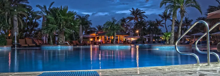 Branded residences in Dubai: the resort pool of a hotel-branded property at dusk