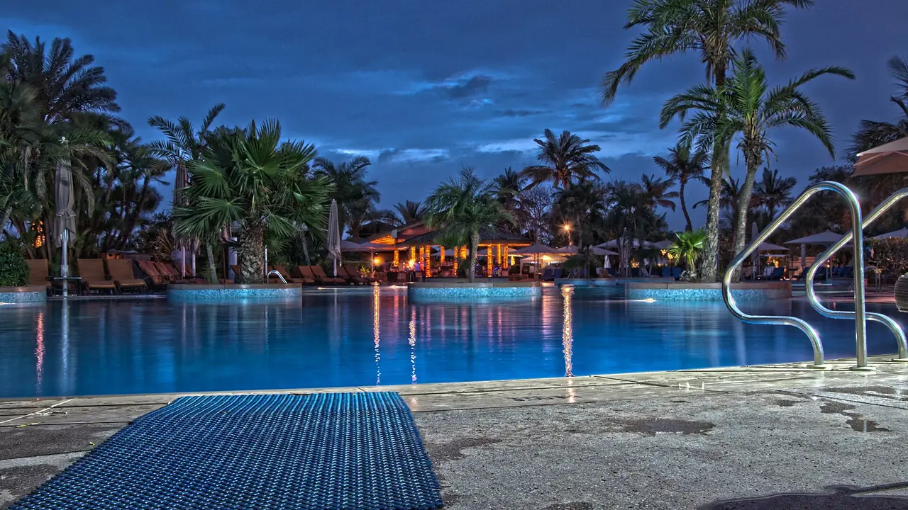 Branded residences in Dubai: the resort pool of a hotel-branded property at dusk