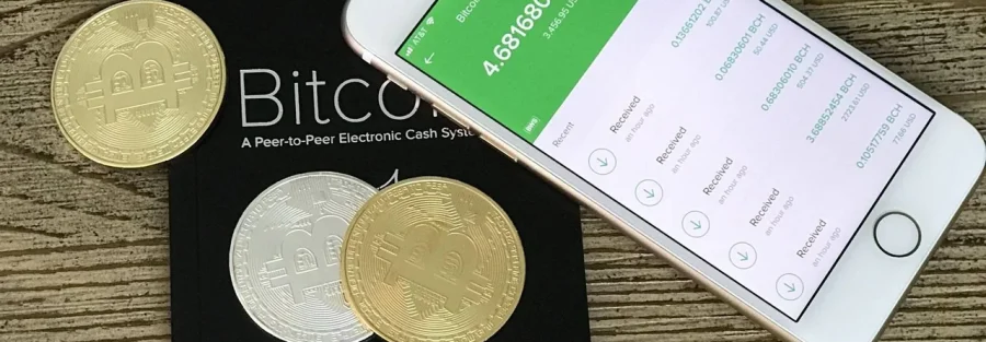 Buying Dubai property with cryptocurrency: gold and silver coins beside a phone showing a crypto wallet