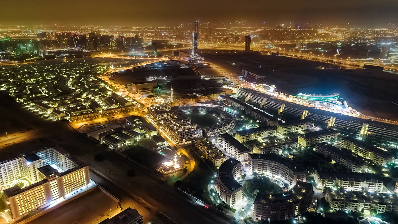 Aerial night view of Dubai Motor City, where buyers and tenants agree the Dubai real estate agent commission before signing