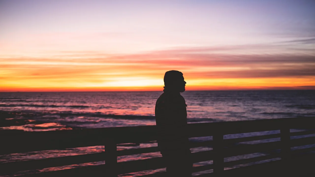 Dubai retirement visa: a person standing on a pier at sunset, looking over the sea